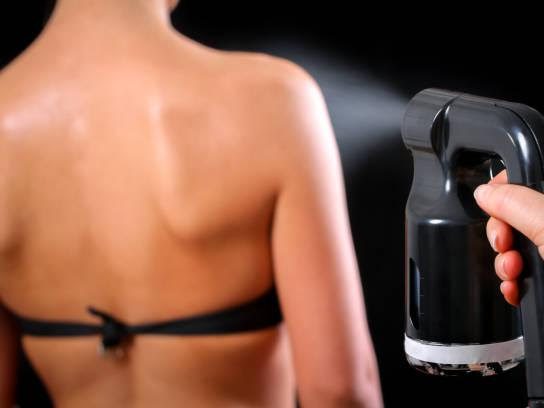 Woman body paint with airbrush in professional beauty salon {{brizy_dc_image_alt imageSrc=